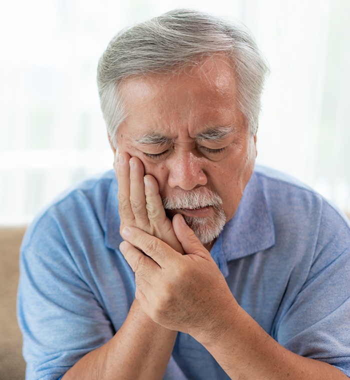 Bearded man rubbing jaw in pain