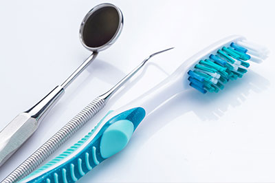 A collection of dental tools, including a toothbrush with blue bristles and a pair of scissors, set against a white background.