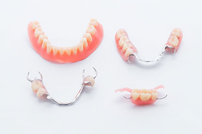 The image displays a set of dentures with visible teeth and gums, presented against a white background on a table.