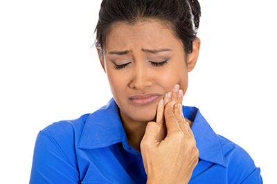 A woman with her eyes closed, looking upwards with a concerned expression, holding her face with her hand, possibly indicating pain or discomfort.