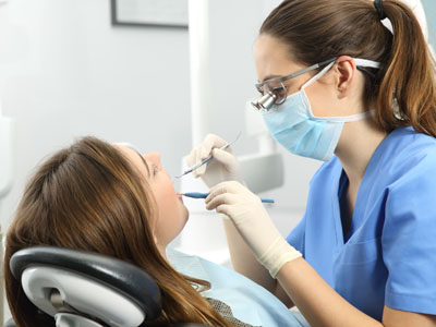 Dental hygienist assisting patient with dental procedure in dental office.