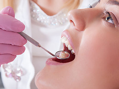 A dental professional is performing a procedure on a patient s teeth using specialized equipment.