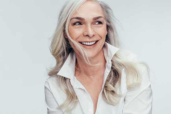 A smiling woman with short hair wearing a white shirt poses against a plain background.