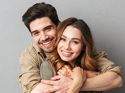 A young couple embracing each other with smiles on their faces, posing for a portrait.