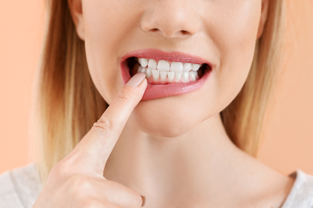 A woman with her finger on her teeth, possibly indicating dental care or oral health.