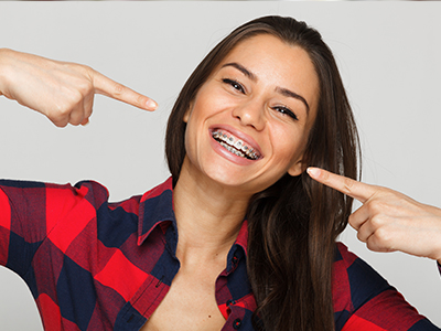 Woman pointing at her teeth with joyful expression.