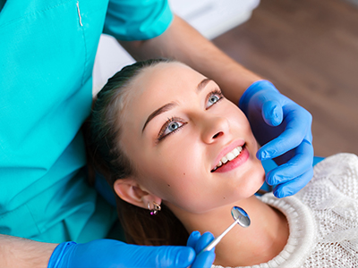 The image depicts a dental professional performing a procedure on a patient s teeth using dental instruments.