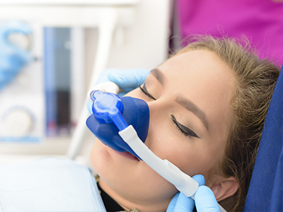 A woman receiving medical care with an oxygen mask on her face, attended by a healthcare professional using a stethoscope.