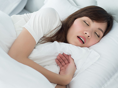 A woman sleeping peacefully on her stomach with her head resting on a pillow.